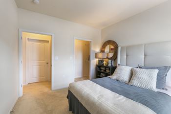 A bedroom with a bed, nightstand, and two doors.